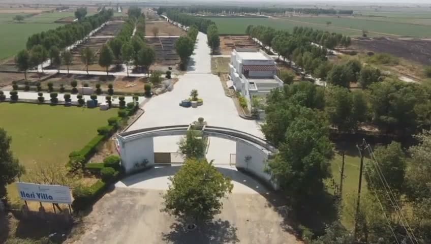 Drone view of Shree Hari Villa: entrance gate, clubhouse and tree-lined roads
